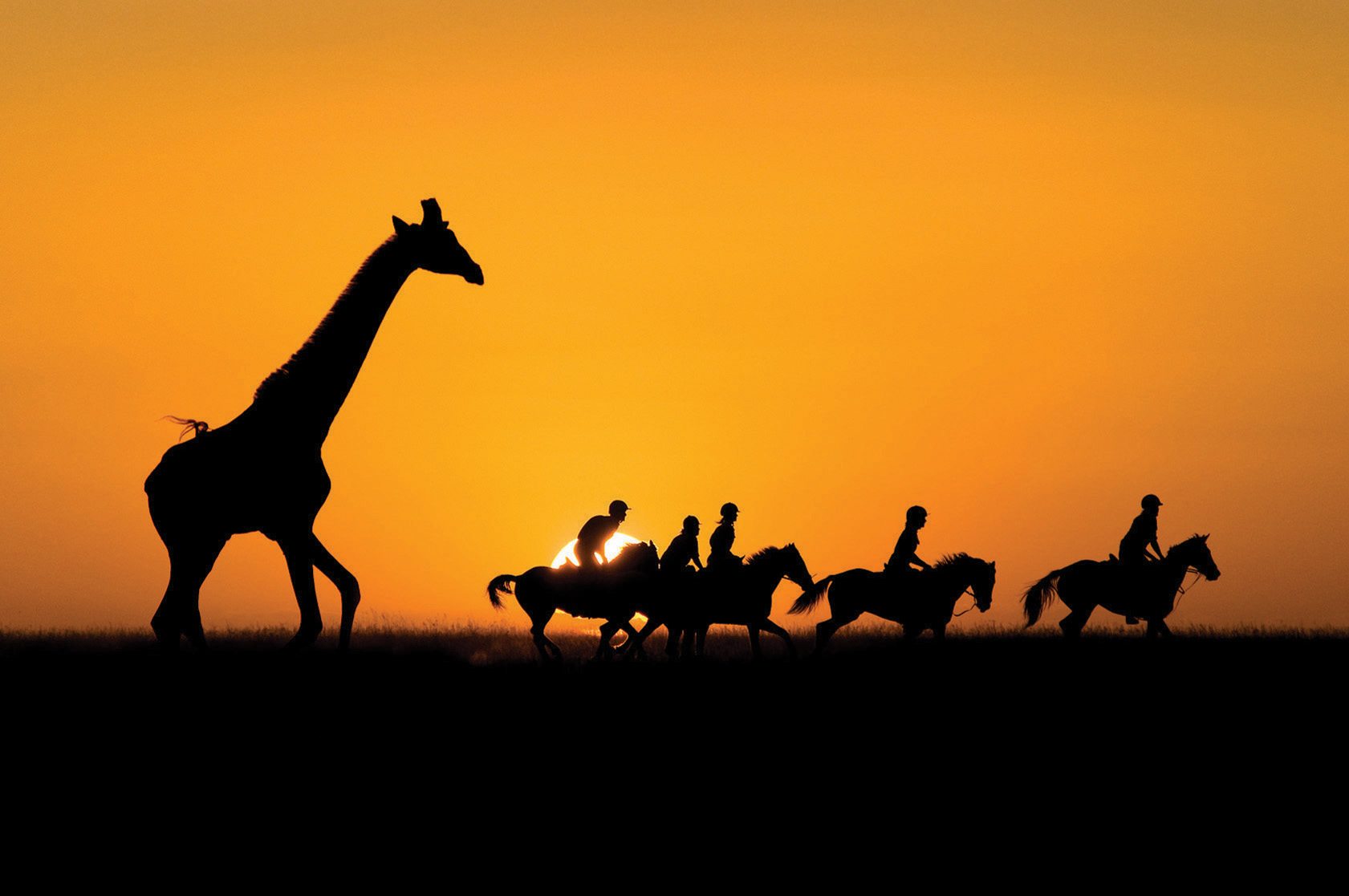 riders with giraffe at sunset horse riding safari kenya by globetrotting